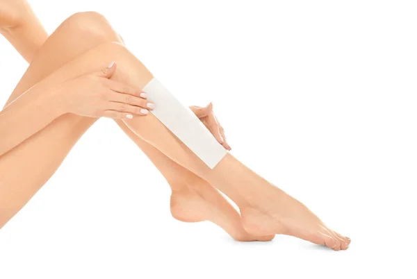 Mujer joven depilando su pierna con franja de cera sobre fondo blanco —  Fotos de Stock
