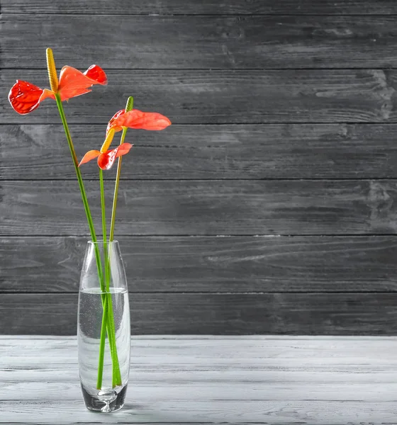 Glass vase with tropical flowers on wooden background — Stock Photo, Image