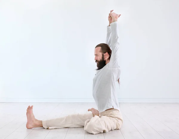 Young man practicing yoga on light wall background — Stock Photo, Image