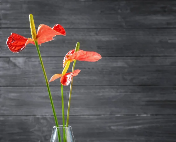 Γυάλινο βάζο με τροπικά λουλούδια σε φόντο ξύλινη — Φωτογραφία Αρχείου