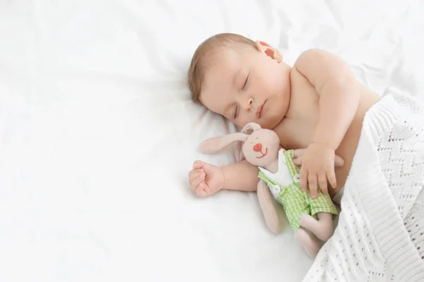 Söt liten baby med leksak som sover på sängen hemma — Stockfoto