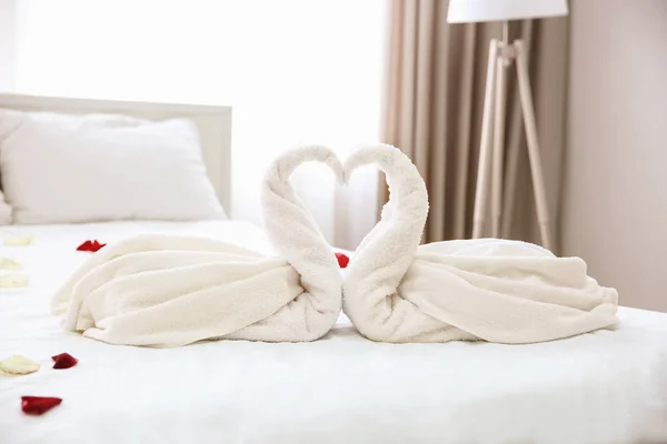 Two towel swans and rose petals on bed in light hotel room — Stock Photo, Image