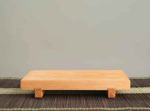 Tablero de madera sobre estera de bambú sobre fondo gris —  Fotos de Stock