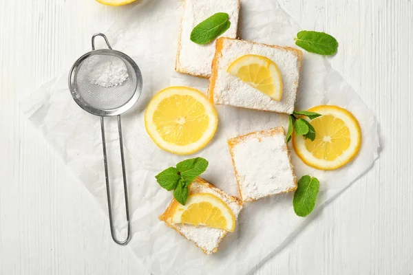 Delicious lemon pie bars and sieve with powdered sugar on wooden table