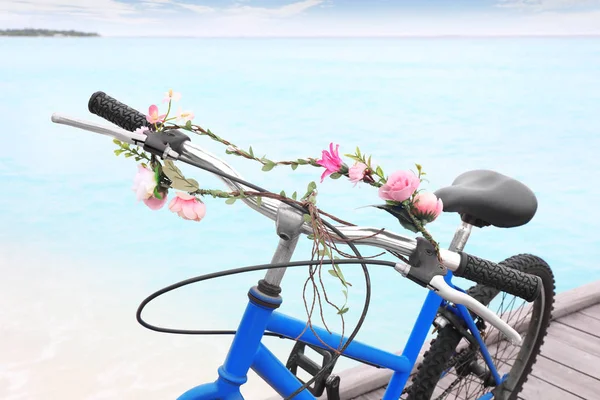 Сучасний велосипед з квітковою гірляндою на морському пляжі — стокове фото