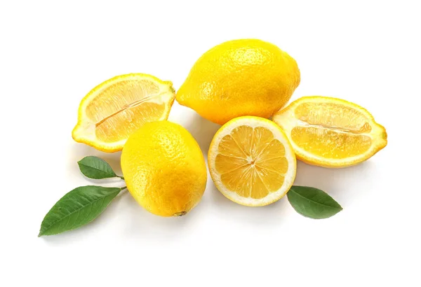 Köstliche geschnittene Zitronen und grüne Blätter auf weißem Hintergrund — Stockfoto
