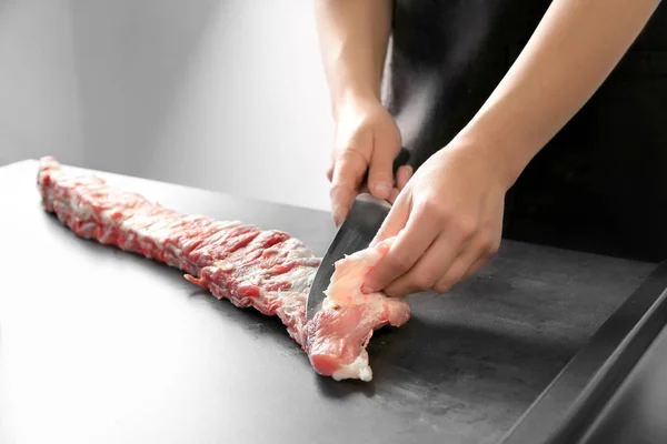 Cocina profesional cortando jugosas costillas de repuesto en la mesa — Foto de Stock