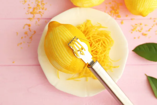 Limón pelado fresco, herramienta especial y ralladura en mesa de madera —  Fotos de Stock