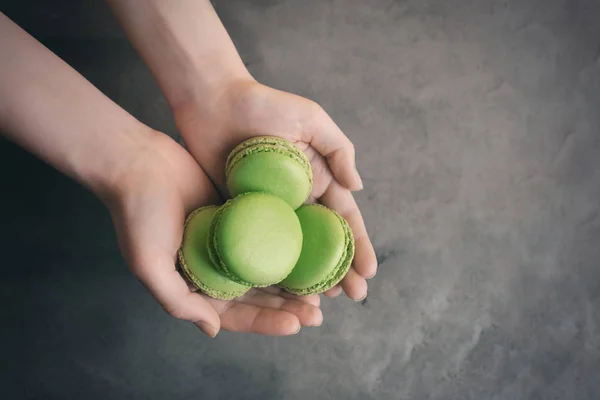 Woman holding tasty green macarons on gray background — Stock Photo, Image