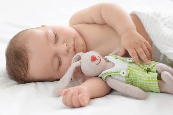 Lindo bebé con juguete durmiendo en la cama en casa — Foto de Stock