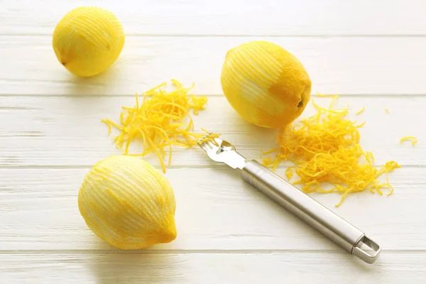 Frisch geschälte Zitronen, Spezialwerkzeug und Lebensfreude auf Holztisch — Stockfoto
