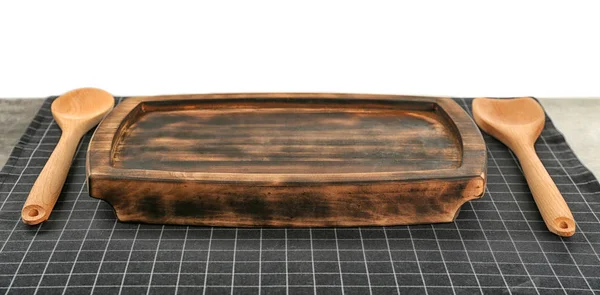 Wooden board and utensils on table with napkin against white background