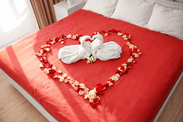 Two towel swans and rose petals on bed in hotel room — Stock Photo, Image