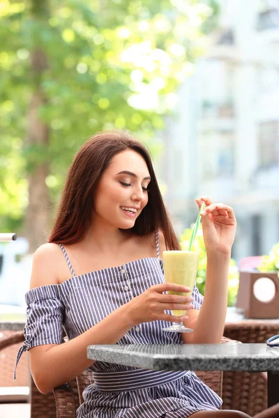 Красивая молодая женщина пьет смузи в кафе — стоковое фото
