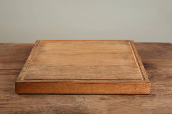 Placa de madeira na mesa contra fundo cinza — Fotografia de Stock