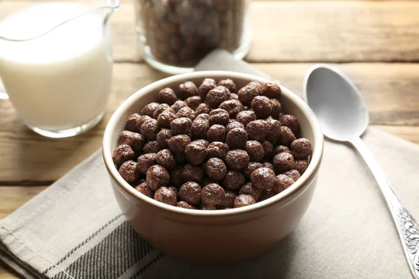 Bolas de milho de chocolate na tigela e jarro com leite na mesa de madeira — Fotografia de Stock