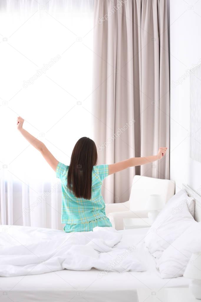 Young beautiful woman awaking in light hotel room