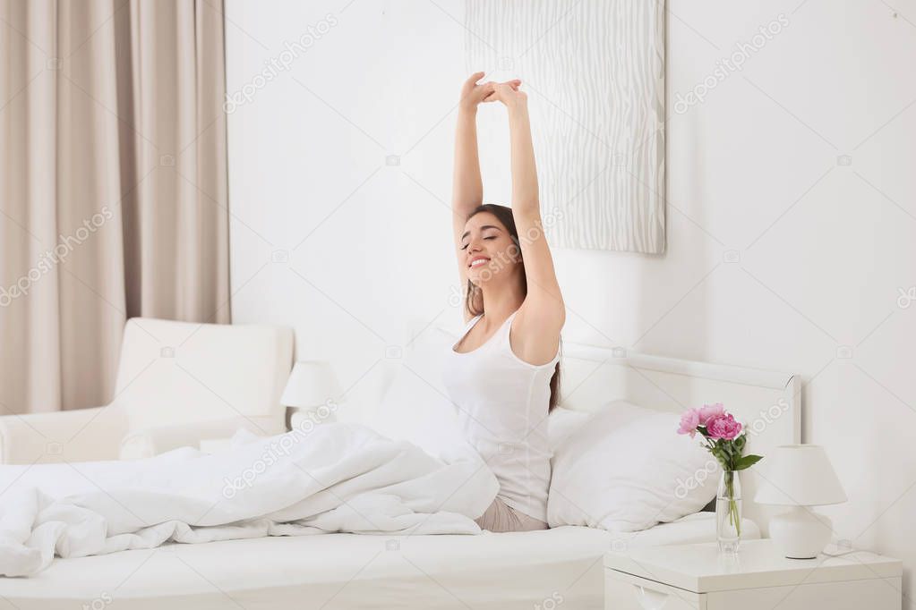 Young beautiful woman awaking in light hotel room