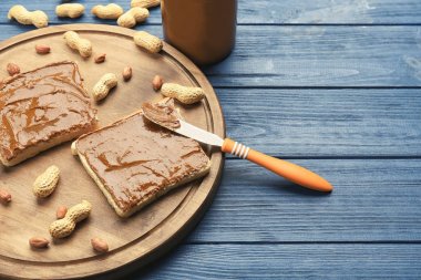 Tost lezzetli fıstık ezmesi, fındık ve ahşap masa üzerinde bıçak ile