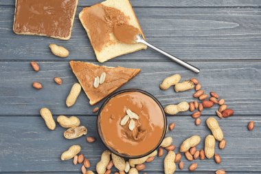 Lezzetli fıstık ezmesi, fındık ve ahşap masa üzerinde tost ile kase