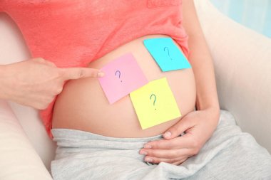Pregnant woman with paper stickers on tummy, closeup. Concept of choosing baby name clipart