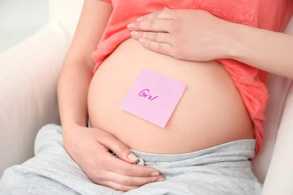 Zwangere vrouw met papieren sticker op buik, close-up. Concept van het kiezen van de babynaam — Stockfoto