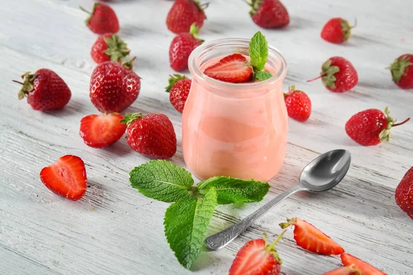 Delicioso yogur con fresa en frasco en la mesa — Foto de Stock