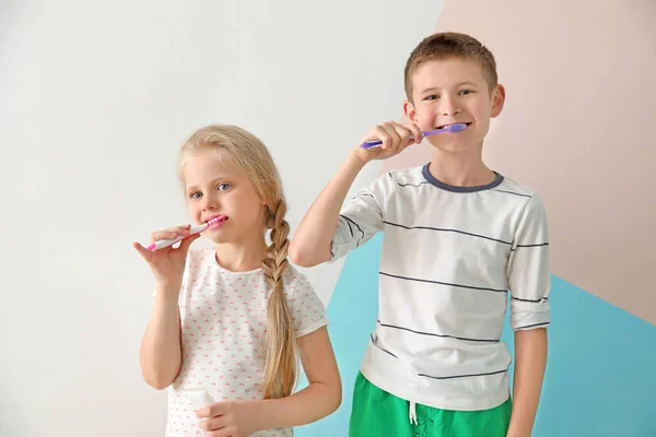 Cute little children cleaning teeth on color background