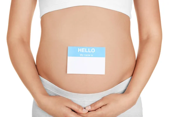Närbild av gravid kvinna med papper klistermärke på magen, mot vit bakgrund. Begreppet att välja baby namn — Stockfoto