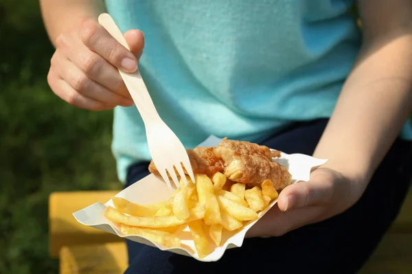 Woman eating fish and chips outdoors