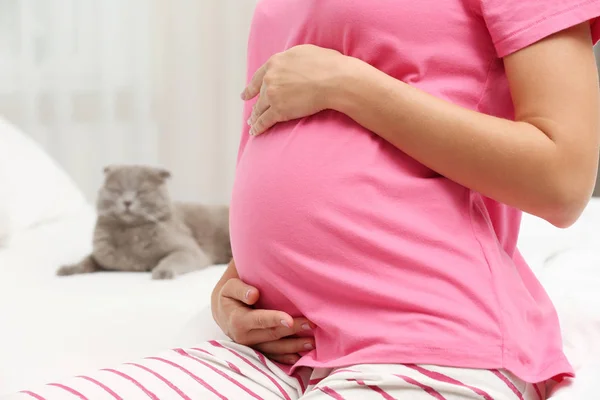 Jonge zwangere vrouw en kat op bed — Stockfoto