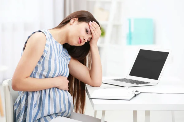 Beautiful young pregnant woman suffering from headache while working with laptop at home — Stock Photo, Image