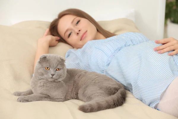 Junge schwangere Frau mit süßer Katze auf dem Bett — Stockfoto