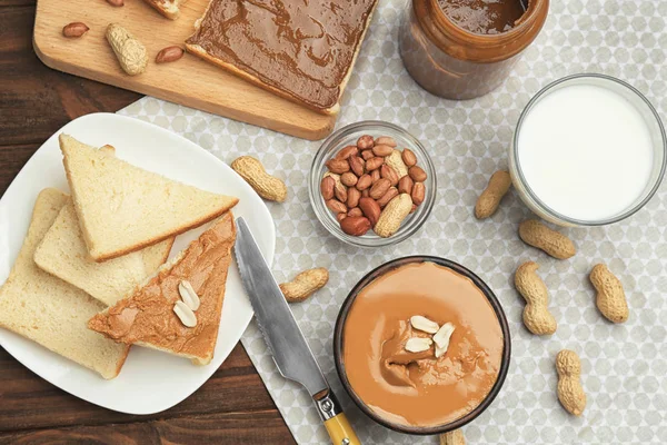 Komposisi dengan selai kacang lezat, roti panggang dan segelas susu di atas meja — Stok Foto
