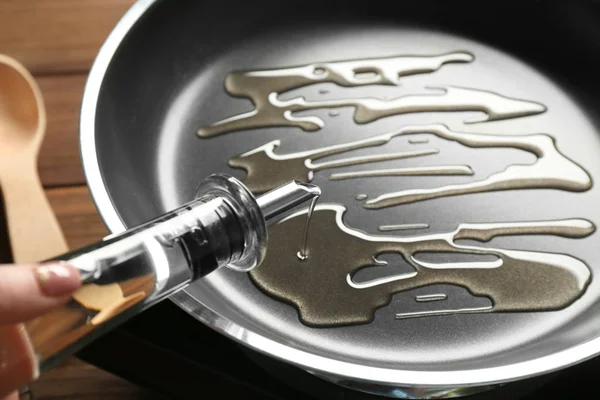Woman pouring oil into frying pan, closeup — Stock Photo, Image