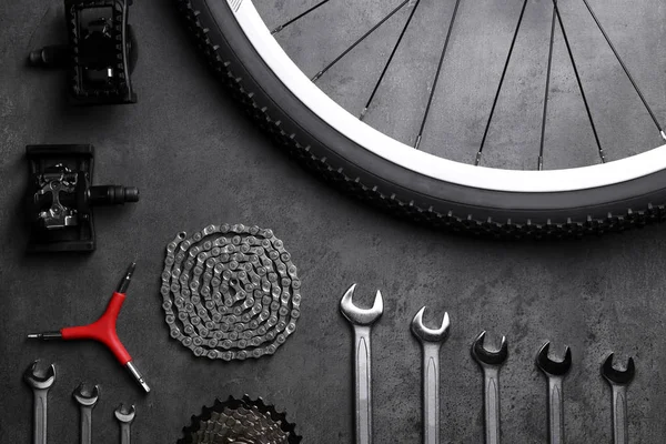 Части велосипеда и инструменты для ремонта на сером фоне — стоковое фото