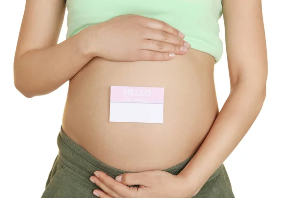 Närbild av gravid kvinna med papper klistermärke på magen, mot vit bakgrund. Begreppet att välja baby namn — Stockfoto