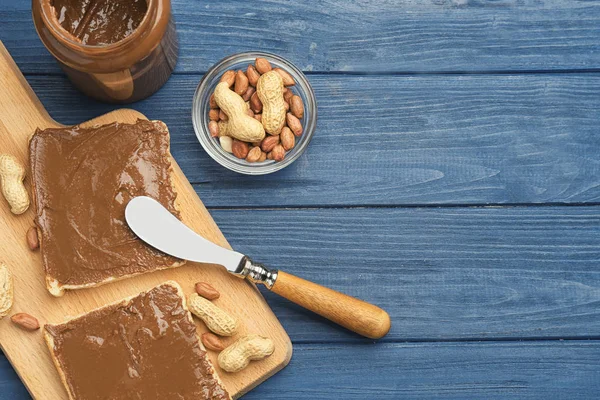 Toasts with delicious peanut butter, jar and nuts on wooden table — Stock Photo, Image