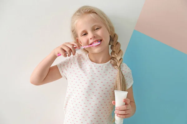 Schattig klein meisje reiniging van de tanden op kleur achtergrond — Stockfoto