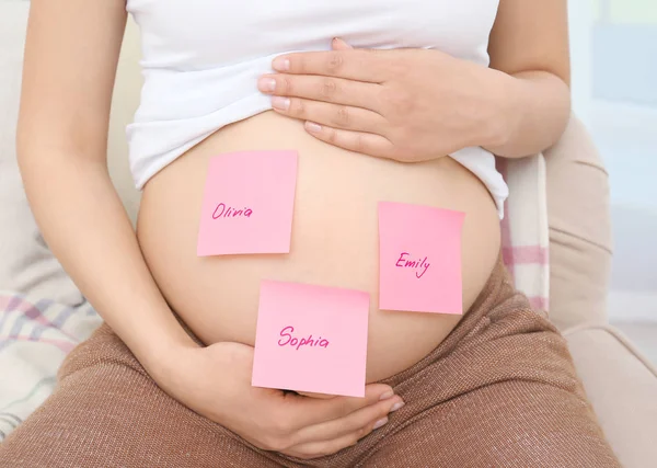 Zwangere vrouw met papieren stickers op buik, close-up. Concept van het kiezen van de babynaam — Stockfoto