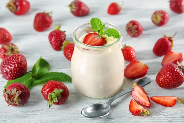 Frasco com delicioso iogurte e morango na mesa de madeira — Fotografia de Stock