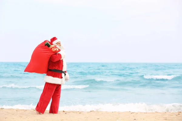 Autentyczny Święty Mikołaj z wielką czerwoną torbę pełną prezenty na plaży — Zdjęcie stockowe
