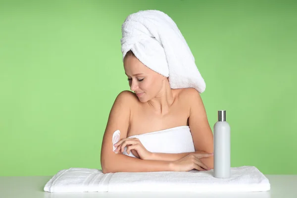 Hermosa mujer joven después del baño con crema corporal sobre fondo de color — Foto de Stock