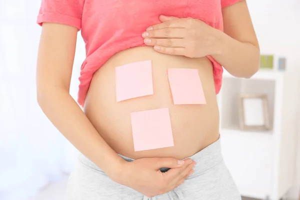 Karın, closeup üzerinde kağıt etiketleri olan hamile kadın. Bebek adı seçme kavramı — Stok fotoğraf