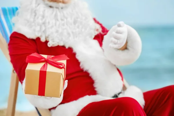 正宗圣诞老人的礼品盒在甲板上的椅子上海滩 — 图库照片