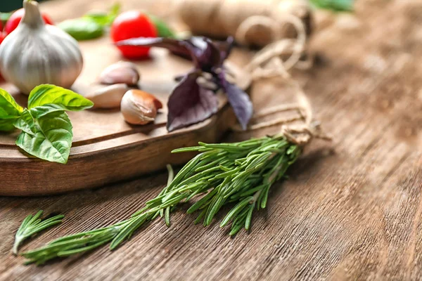 Verschiedene frische Kräuter mit Knoblauch auf Holztisch — Stockfoto