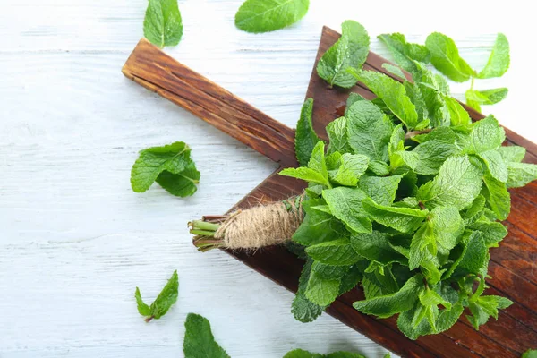 Bunch of fresh mint and wooden  board on table — Stock Photo, Image