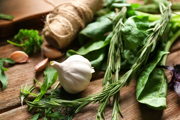 Olika färska örter med vitlök på träbord — Stockfoto