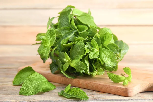 Manojo de menta fresca y tabla en la mesa de madera — Foto de Stock