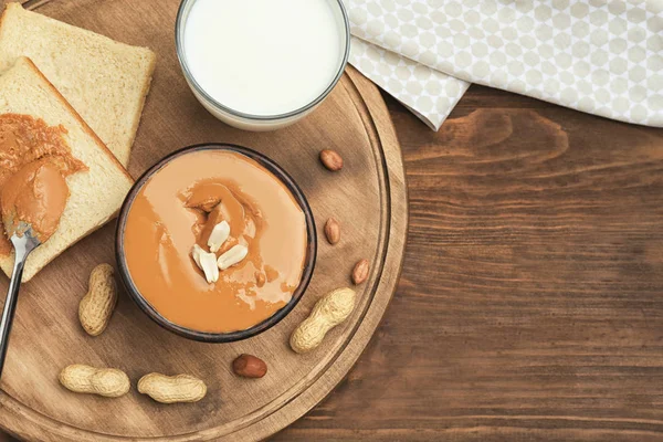 Schüssel mit leckerer Erdnussbutter, Toasts und einem Glas Milch auf dem Tisch — Stockfoto